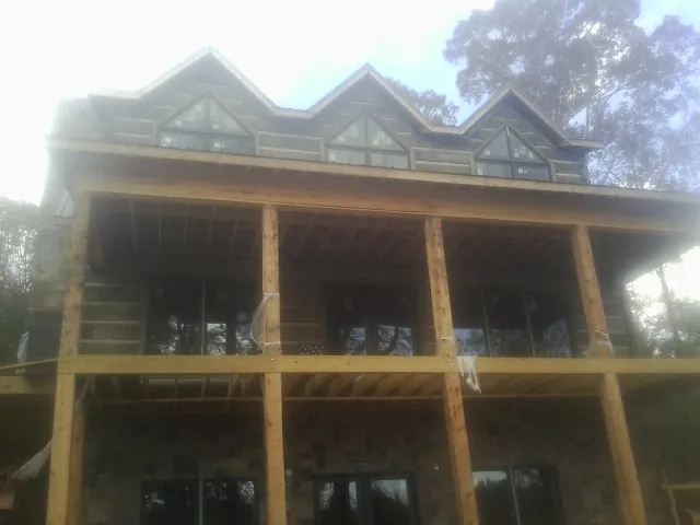 Dormers and porch framing on a large log home under construction — Roof Coating work by our crew in Fort Harrison