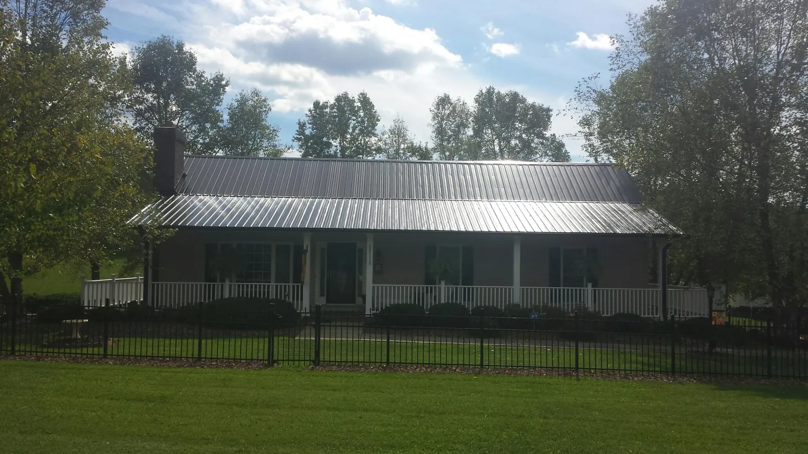 Gray metal roof on a brick ranch with a full width front porch — Gutter Guard Installation work by our crew in Fort Harrison