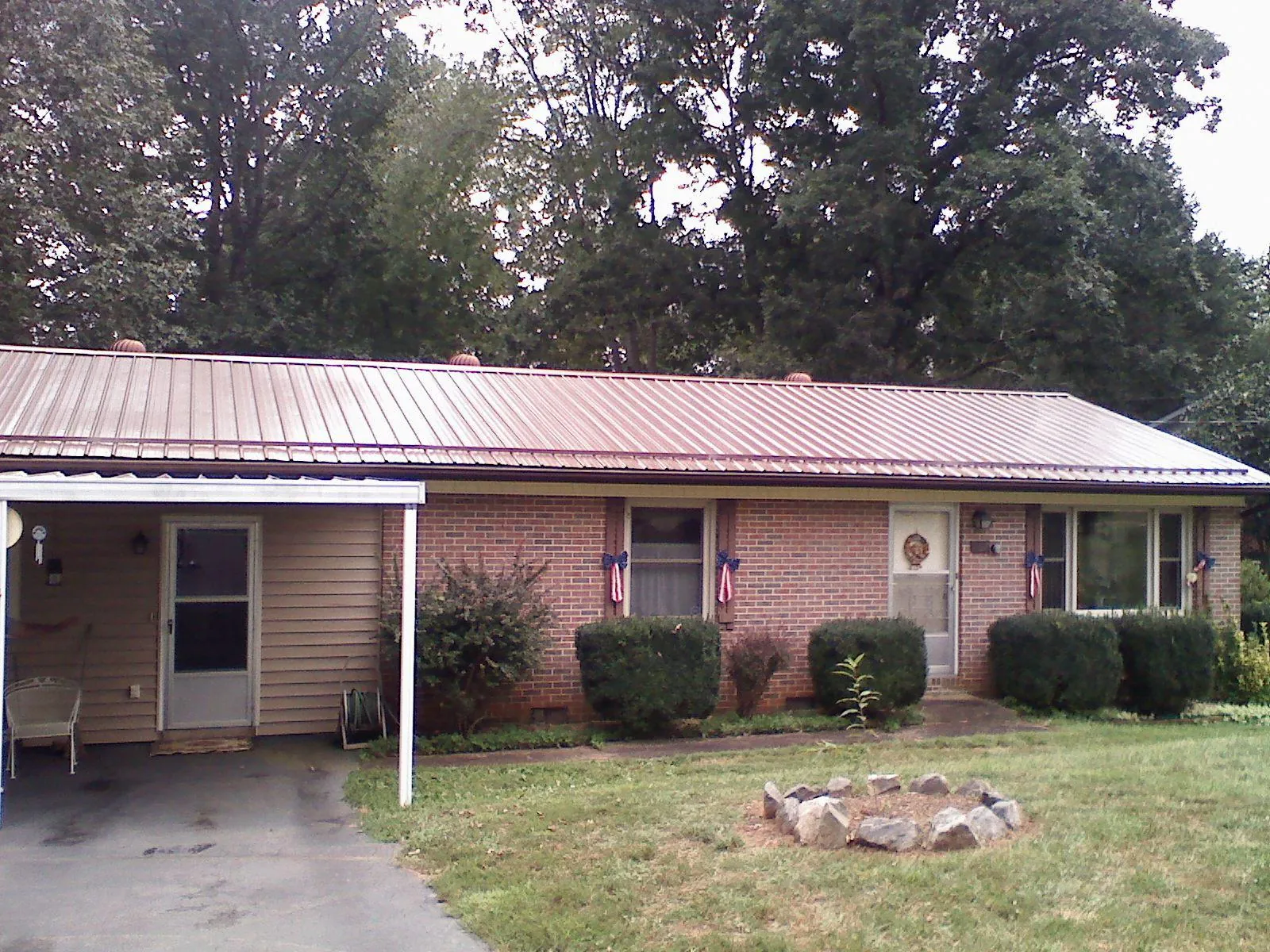 Bronze metal roof and carport on a brick ranch home — Roof Repair work by our crew in Fort Harrison