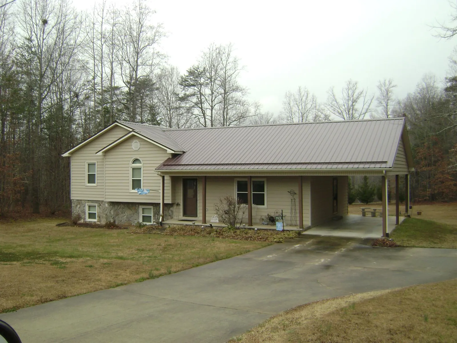 Brown metal roof on a tan split level home with an attached carport in Fort Harrison